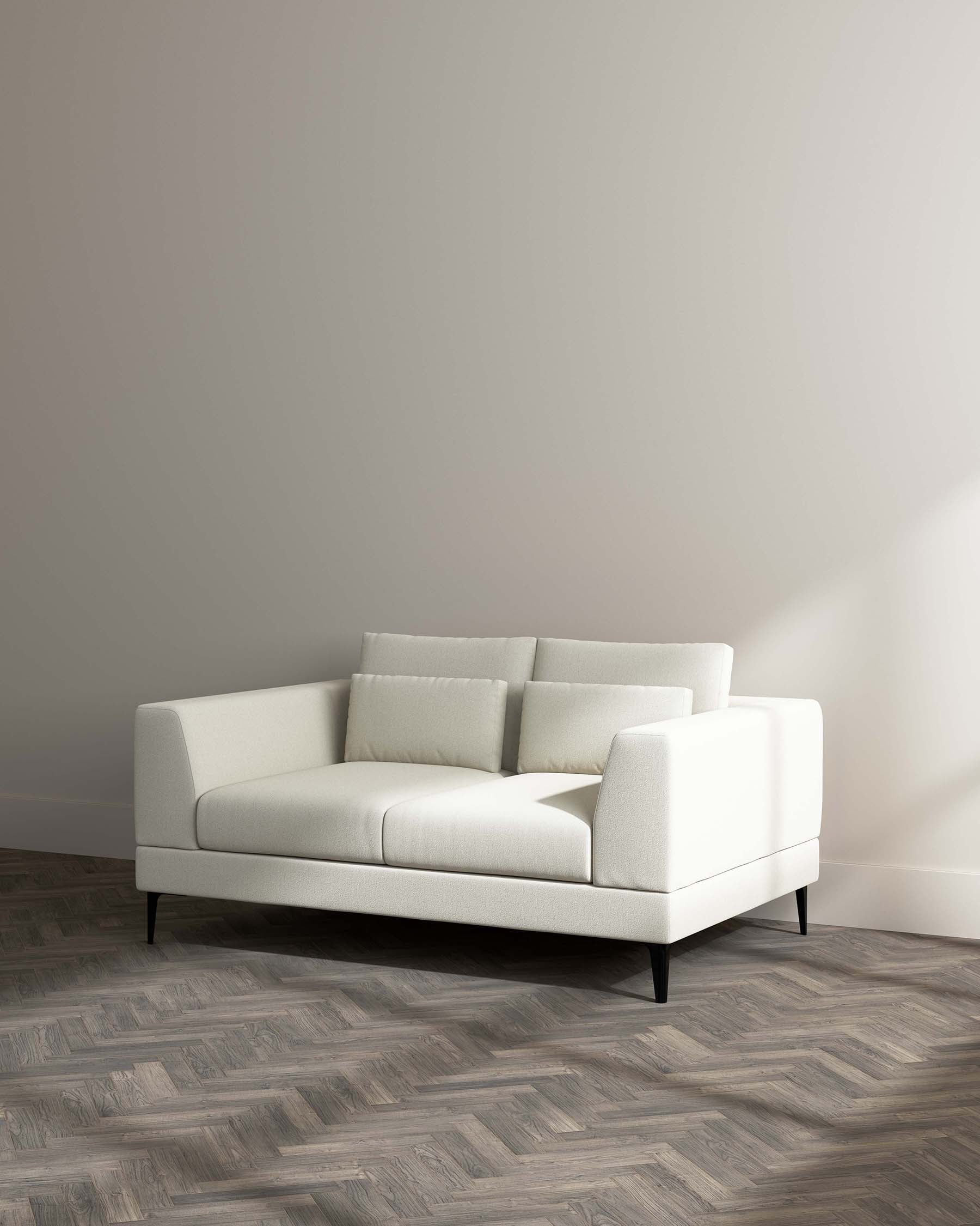 Modern minimalist off-white three-seater sofa with clean lines, tapered black legs, and two matching throw pillows set against a neutral beige wall on a herringbone-patterned wood floor.