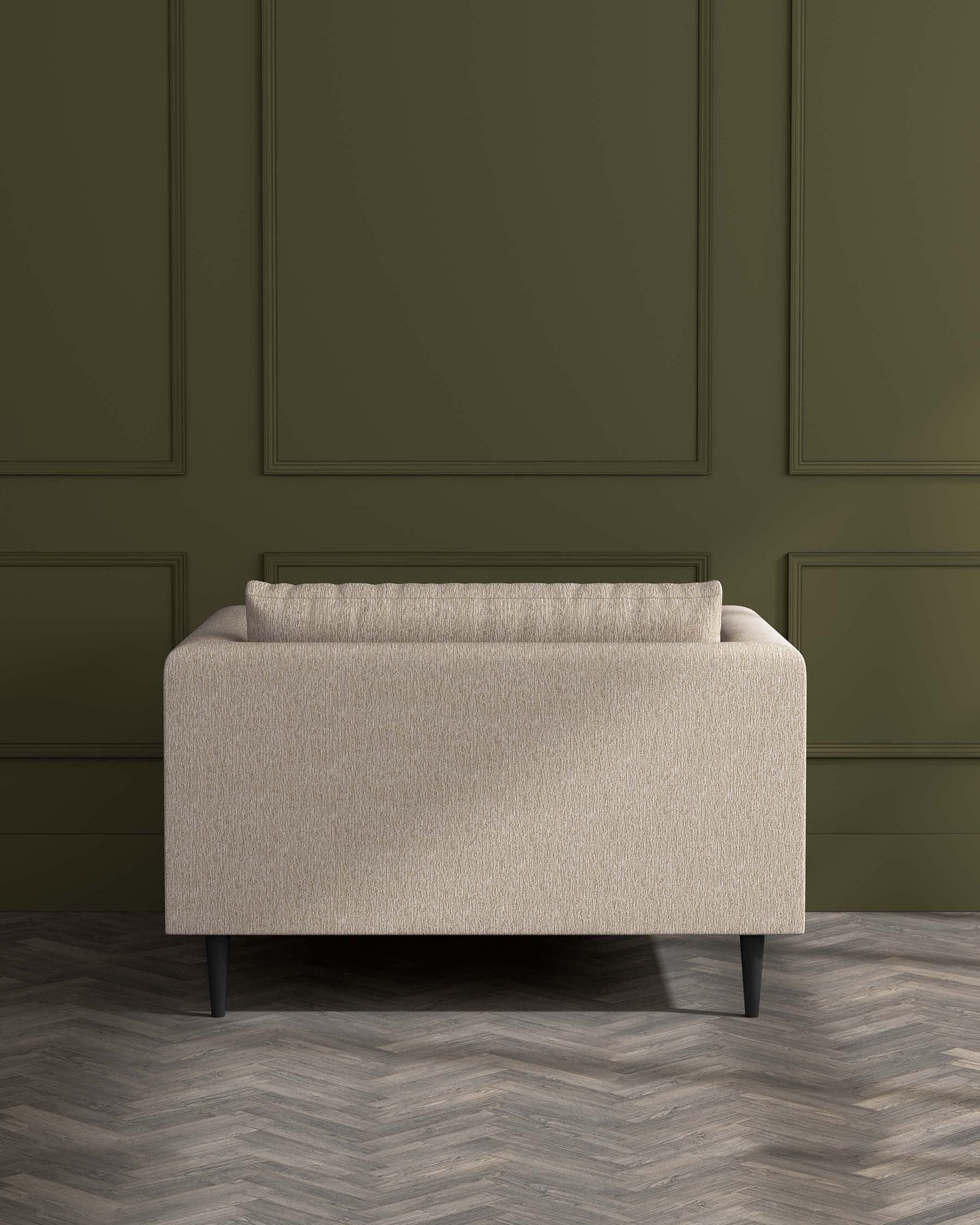 Modern beige fabric loveseat with clean lines and dark wooden tapered legs set against a green wainscoted wall on a herringbone patterned wooden floor.