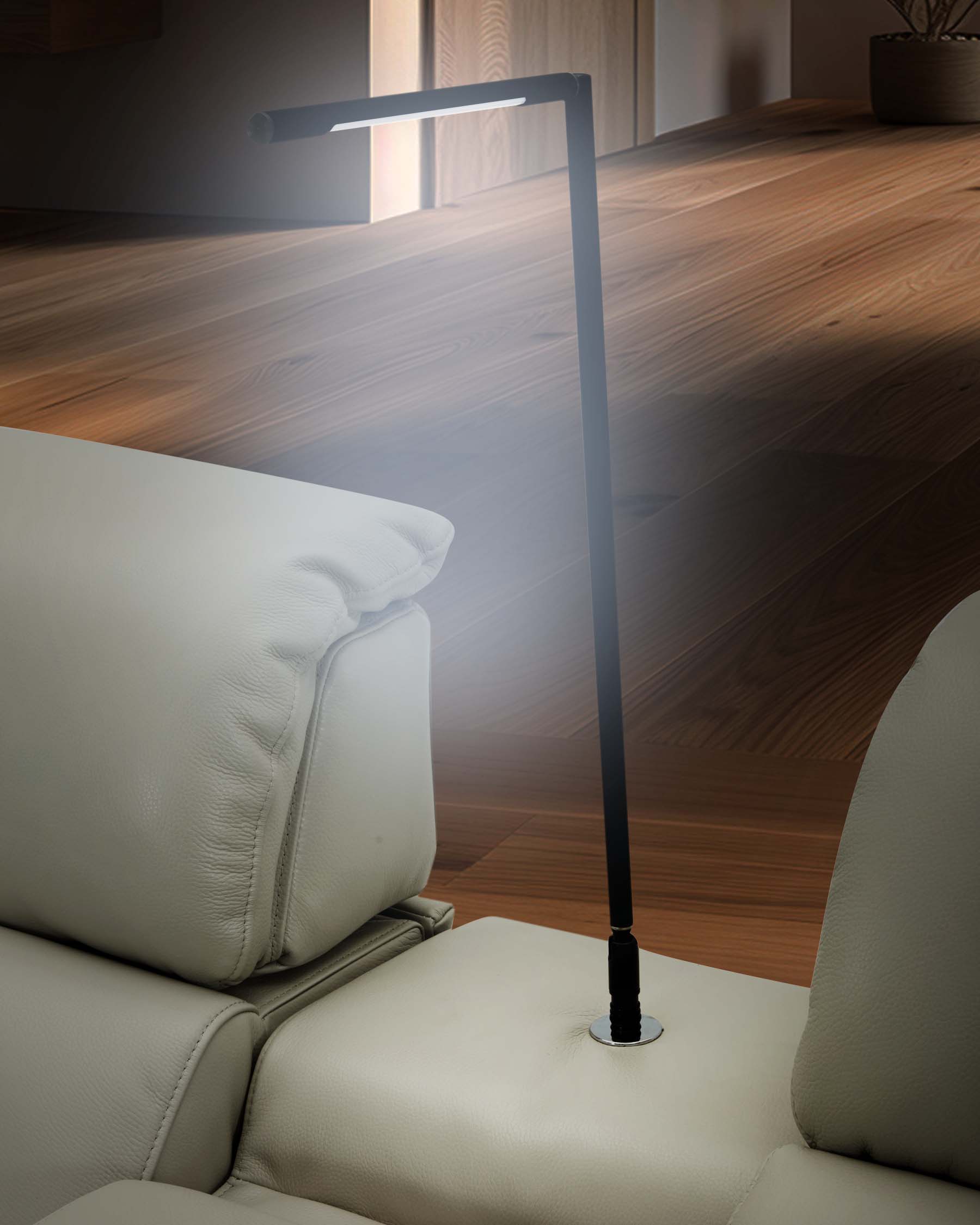 A modern leather sofa with a sleek, adjustable reading lamp integrated into the armrest for convenience and style.