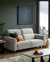 A soft, light gray sofa with plush cushions, accented by dark and rust-colored throw pillows, alongside a sleek coffee table.