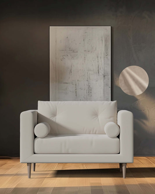 A modern light gray sofa with round side cushions, featuring a minimalist design and wooden legs, set against a muted backdrop.