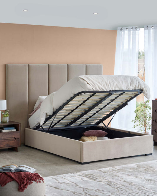 Stylish beige upholstered bed with a lift-up storage base, accompanied by a wooden nightstand and soft decor accents.