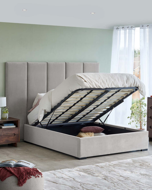 A modern bed with a plush headboard and lift-up storage base, accompanied by a wooden nightstand and cozy decor.