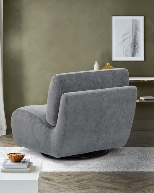 A sleek, modern gray swivel chair on a light rug, complemented by a side table displaying decorative items and a framed print.