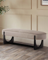 A sleek, beige upholstered bench with a modern black base, perfect for stylish seating in any room.