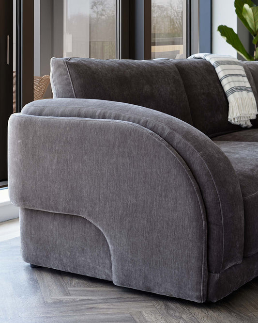 Stylish gray upholstered sofa with rounded edges, featuring plush cushions and a contemporary design, set against a light wood floor.