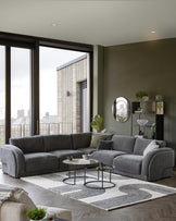 Modern gray sectional sofa with accent pillows, circular coffee tables, and a stylish area rug in a contemporary room setting.