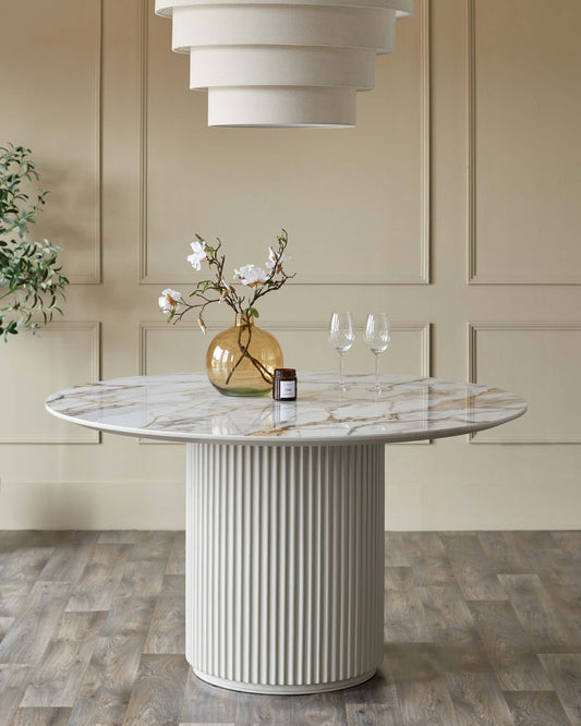 Elegant round table with a marble top and ribbed base, complemented by a stylish pendant light and decorative vase.