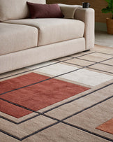 Contemporary beige sofa with plush cushions and a geometric-patterned area rug featuring beige, rust, and cream squares.