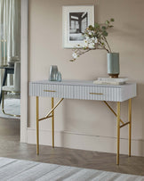 Stylish console table with a sleek white finish, gold legs, and decorative accessories including a vase and books.