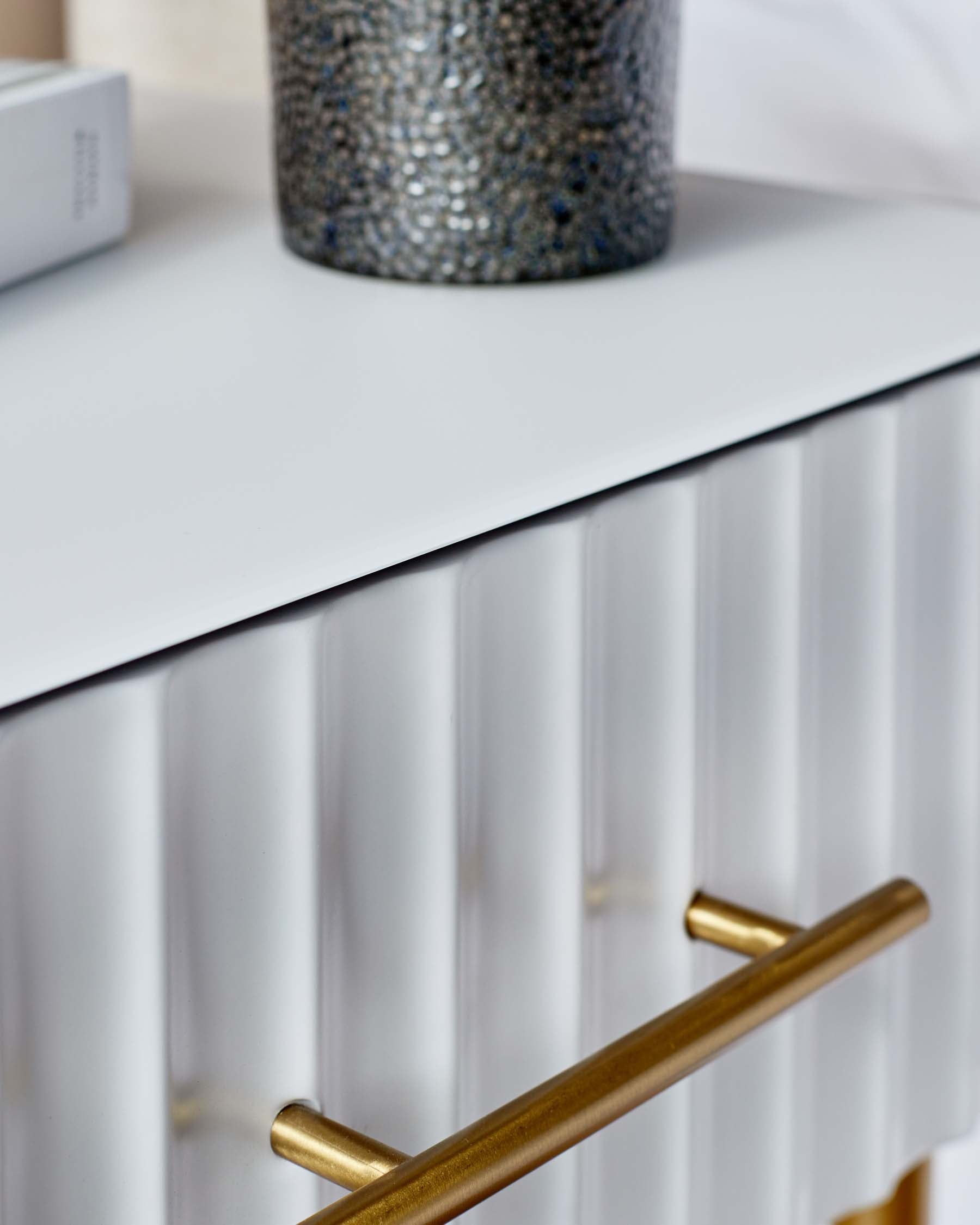 Modern white sideboard with textured front panels and brass handles.