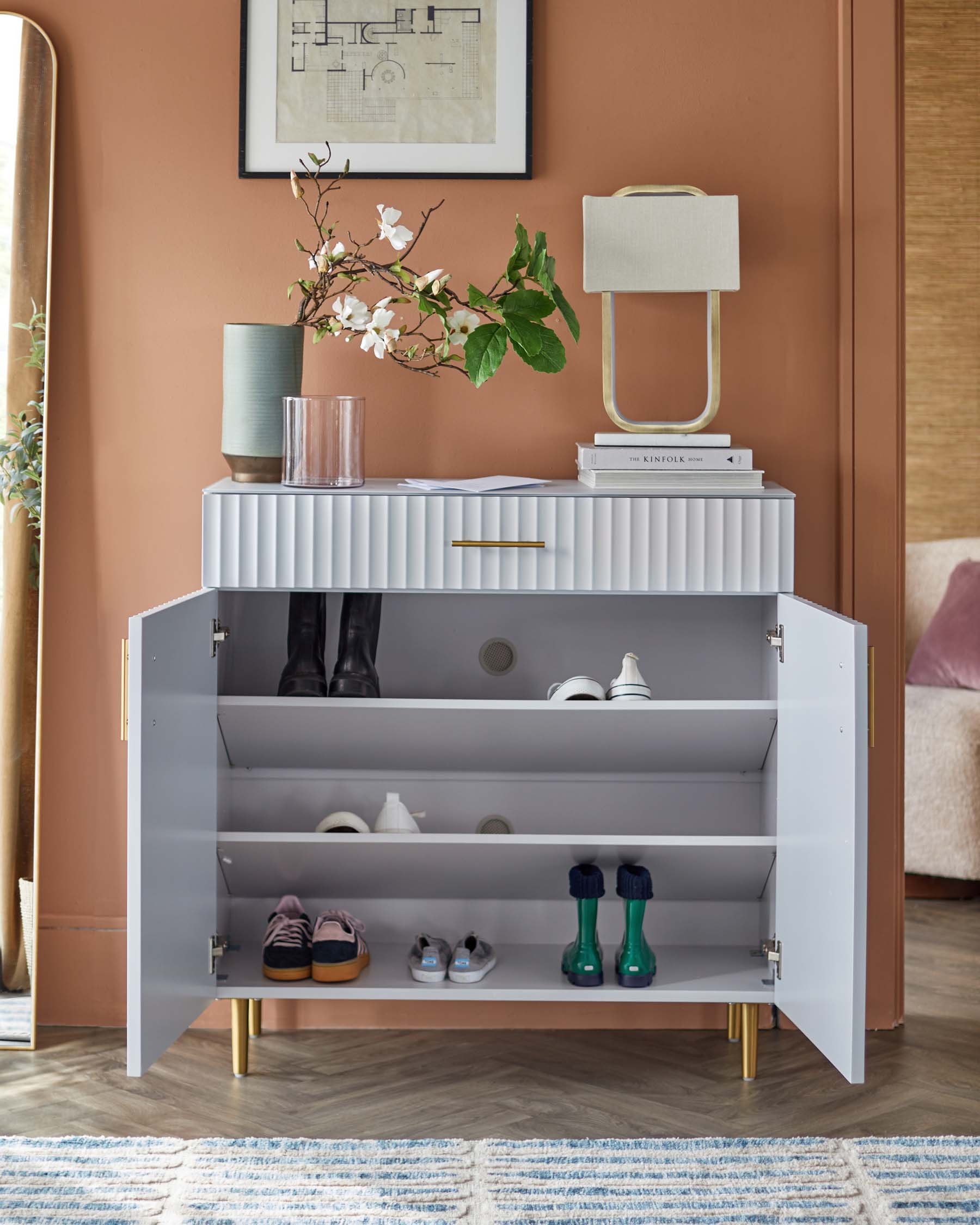 Modern storage cabinet with a ribbed front, gold handles, and legs; includes decorative items like a lamp and vases.