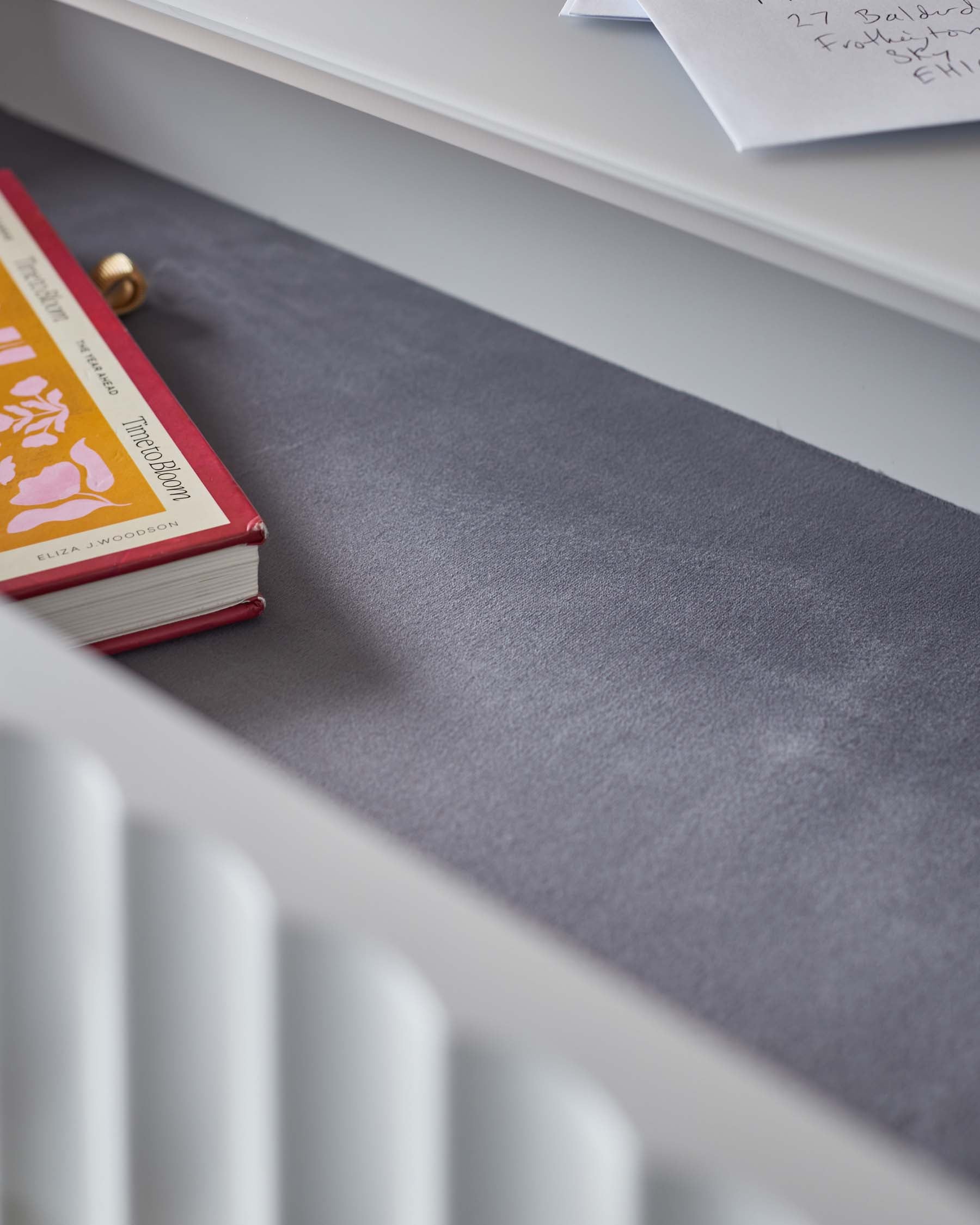 A sleek drawer with a soft gray interior, featuring a colorful book and scattered papers, highlighting modern and minimalistic design.