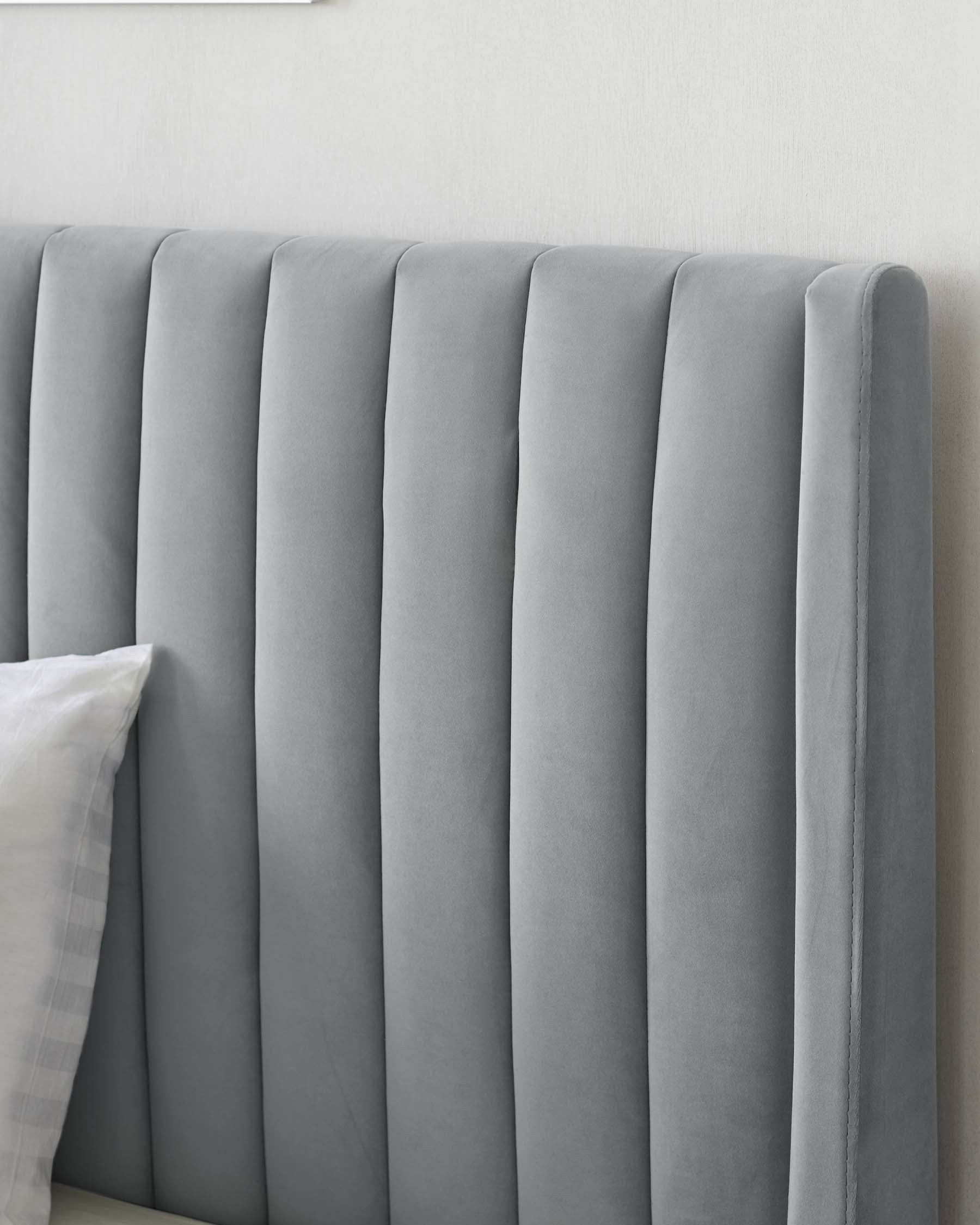 A modern grey upholstered headboard with a vertical channel design.