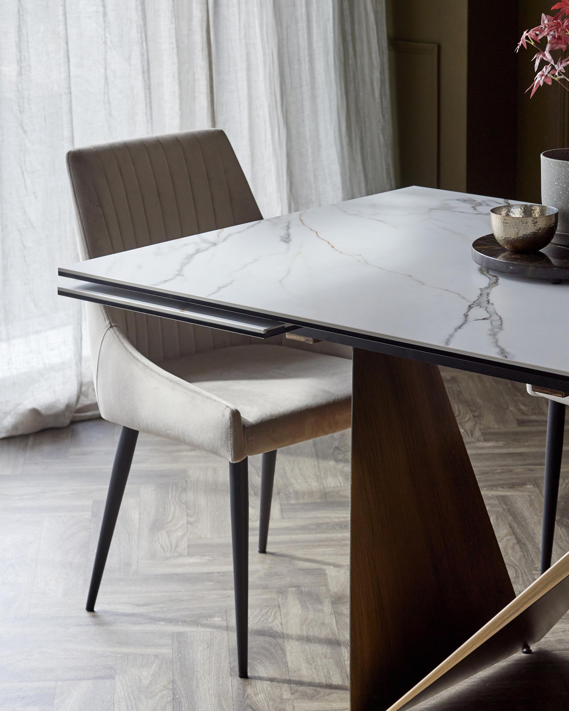 Stylish dining setup featuring a modern marble-top table and a chic, upholstered chair with vertical stitching.