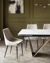 A modern dining set featuring a marble top table with sleek gold legs and plush, upholstered chairs in soft beige.