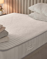 A cozy mattress with a textured surface, layered with soft pillows, complemented by a plush, tufted headboard.