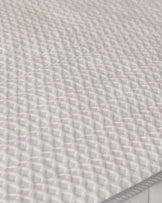 Textured white mattress with a diamond pattern, emphasizing comfort and support for a restful sleep experience.