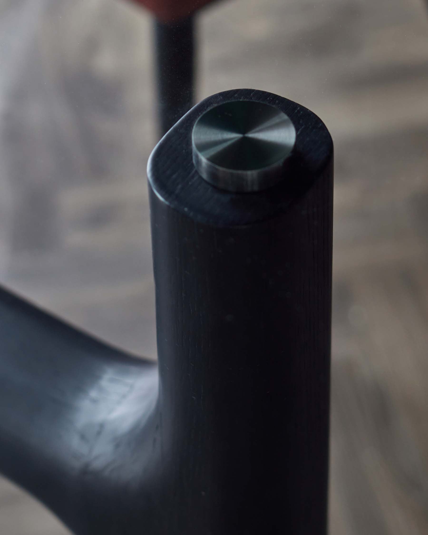 Close-up of a sleek black furniture leg, featuring a polished metal cap, highlighting modern design and craftsmanship.