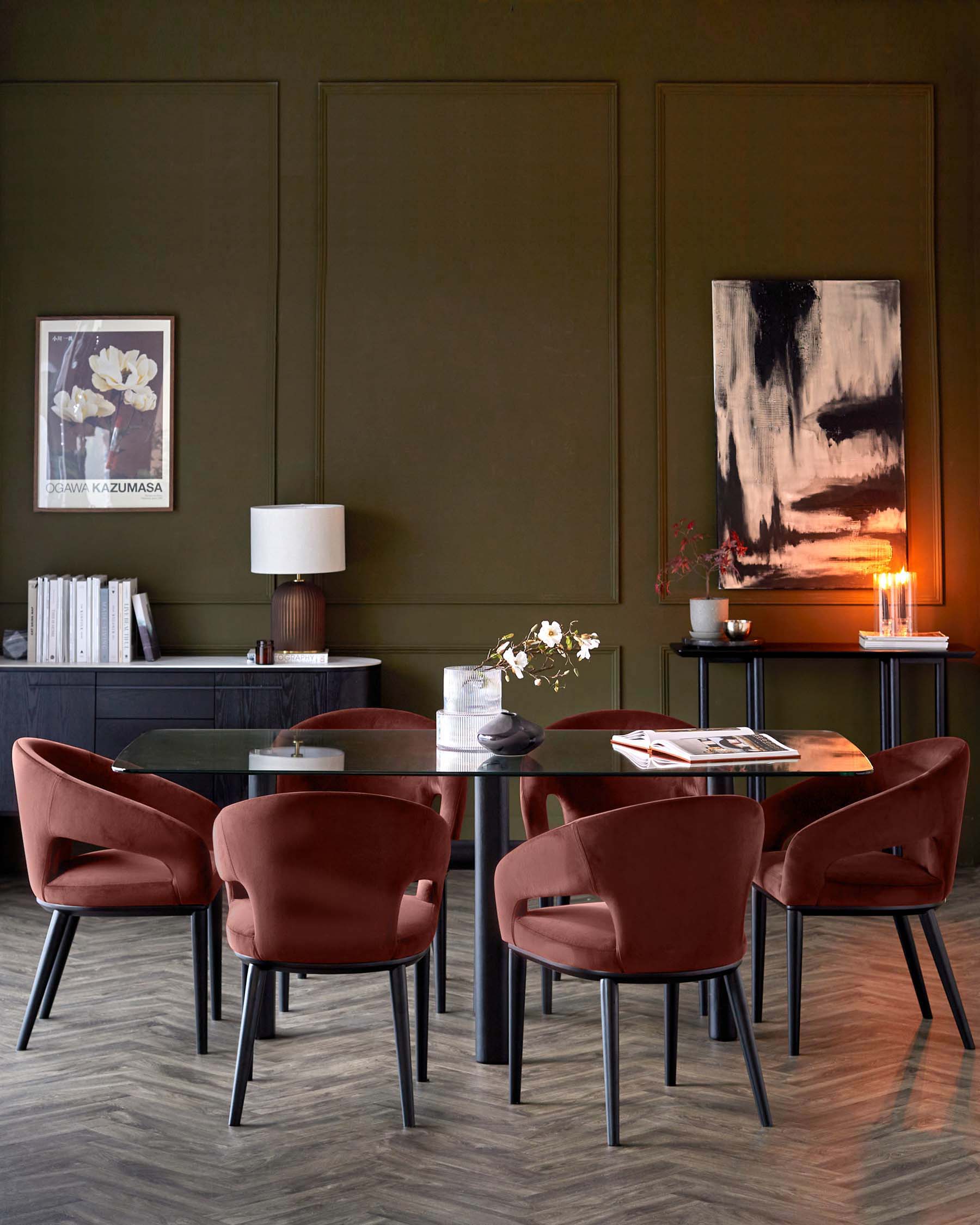 Modern dining table with glass top, surrounded by four plush, rust-colored chairs, complemented by stylish decor and lighting.