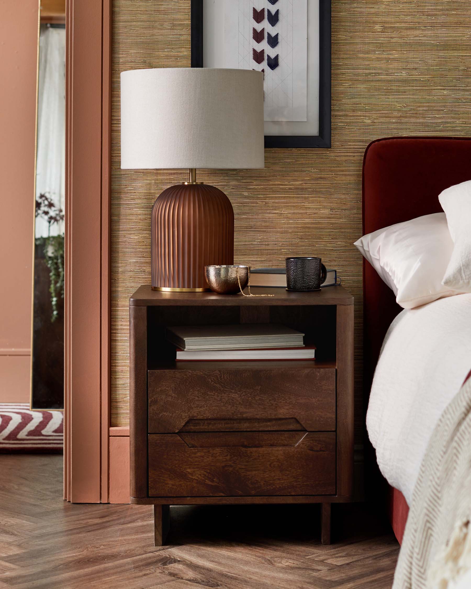 A modern nightstand with a textured dark wood finish, a ribbed lamp, decorative items, and open/closed storage.