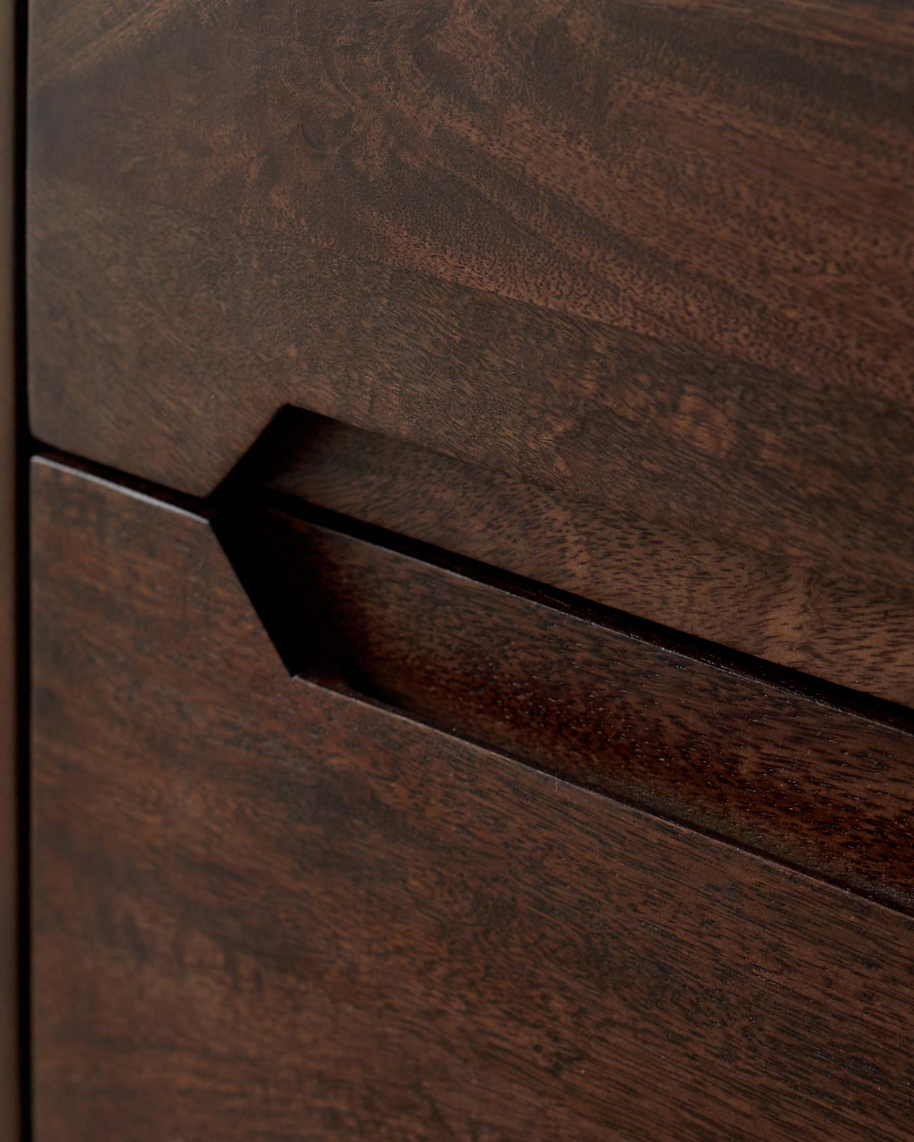 Close-up of a dark wood cabinet door featuring a sleek, modern handle design with a geometric cutout.