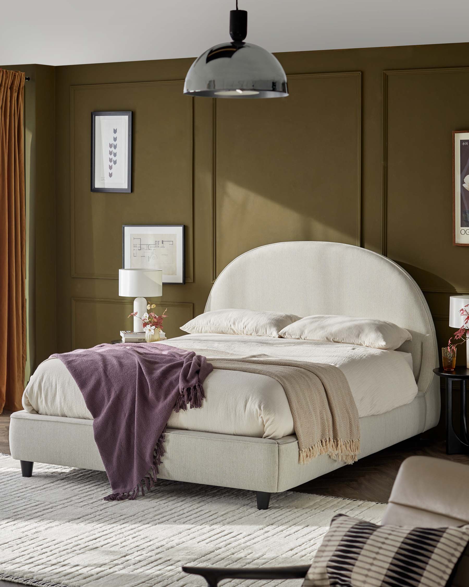 A modern bed with a curved headboard, layered with soft blankets and pillows, complemented by a sleek lamp and stylish decor.