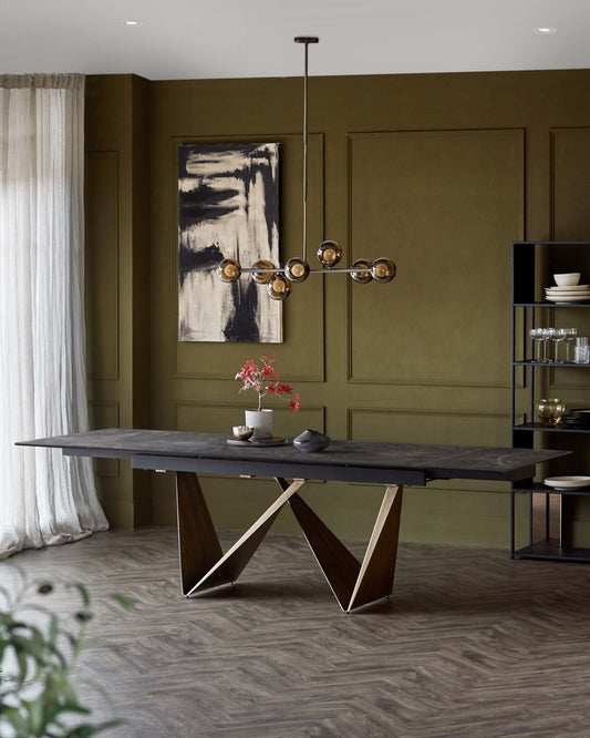 A sleek black dining table with a unique base, modern pendant light above, and a minimalist shelving unit in an olive green room.