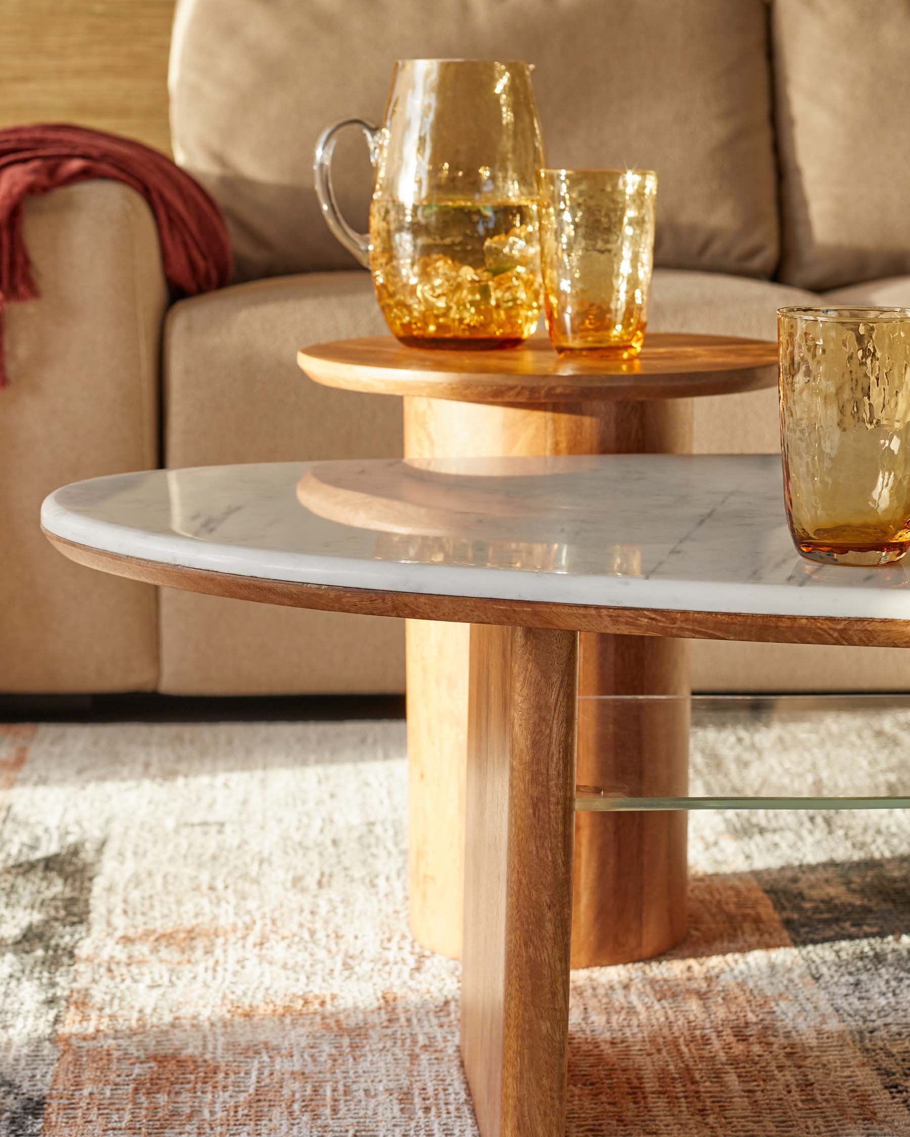 Stylish coffee tables featuring a marble top and wooden base, accented with golden glassware on one table.