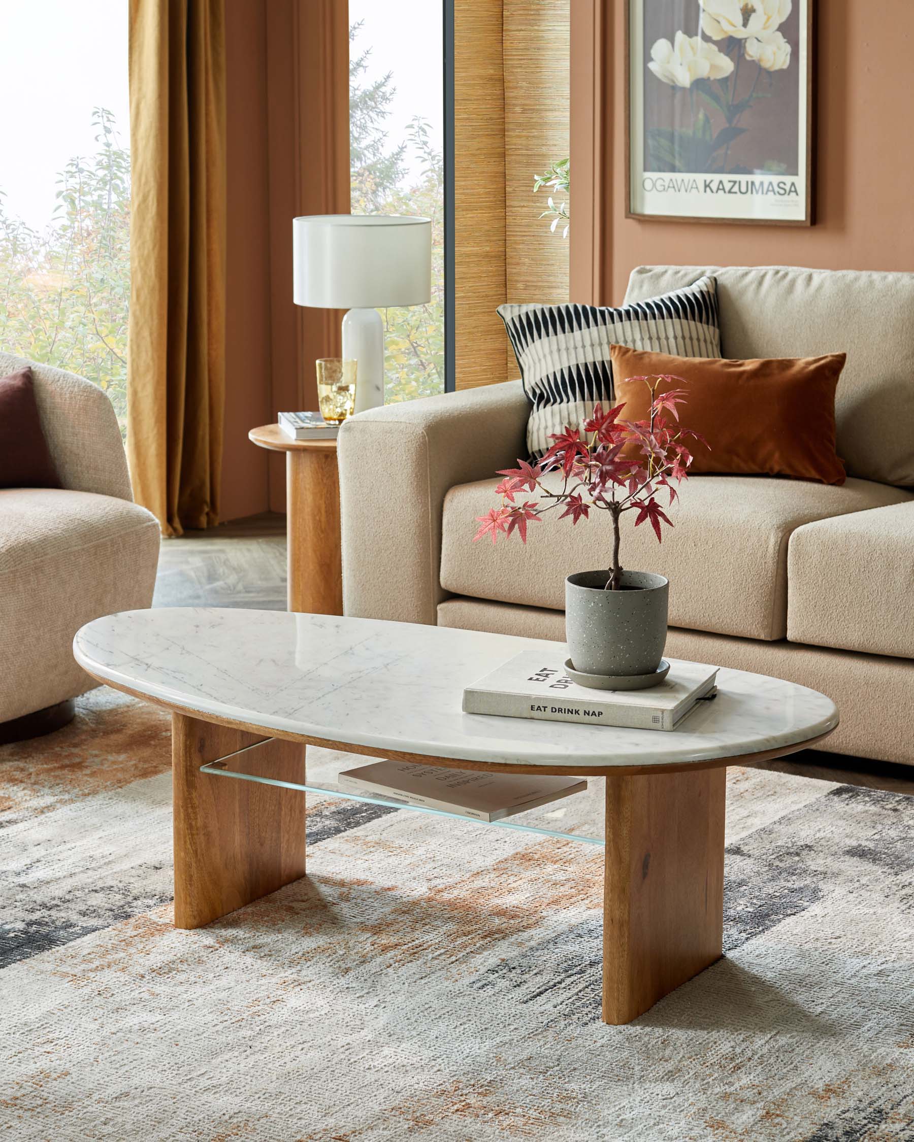 Modern living room setup with a marble-top coffee table, plush sofa, accent pillows, lamp, and a decorative plant.