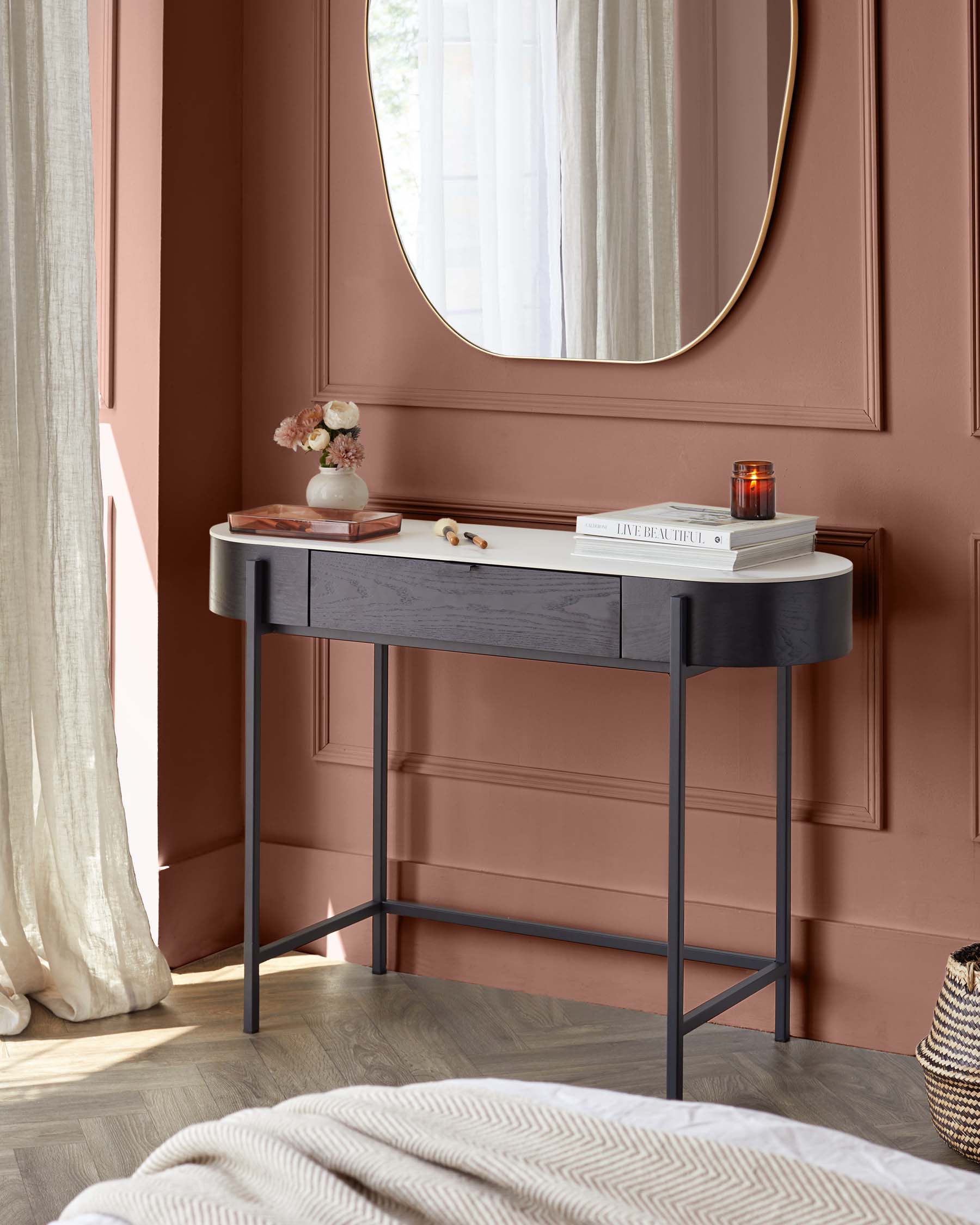 Contemporary slender console table with a contrasting colour design, featuring a smooth grey upper drawer and a darker grey lower body, supported by a minimalist metallic black frame and legs. The tabletop is adorned with decorative items including books, a vase with flowers, and a candle.