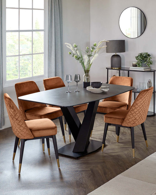 Modern dining set featuring a sleek black table and four elegant, copper velvet chairs with gold accents.