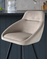 Elegant modern dining chair with a curved backrest and a comfortable, cushioned seat in a light beige velvet fabric, featuring dark, tapered metal legs.