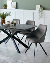 A modern dining table with a black base and an angular design, accompanied by sleek gray chairs featuring curvy backs.