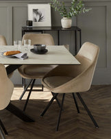 Contemporary dining room set featuring a rectangular marble-top table with a black metal base, complemented by four velvety beige upholstered chairs with black metal legs. A sleek black console table is positioned against the wall in the background.