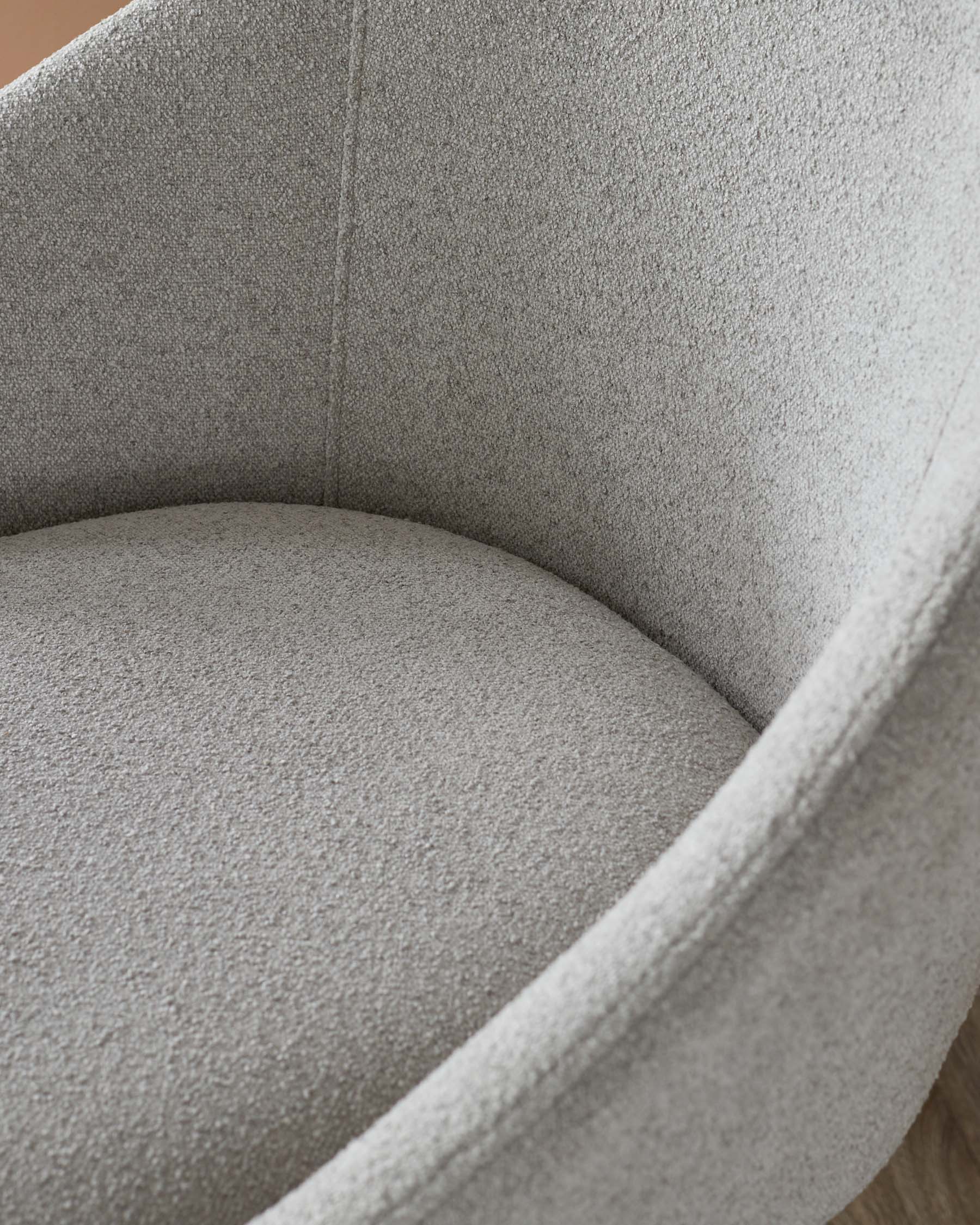 Curved, soft-textured armchair in muted gray upholstery, designed for comfort with a cozy, inviting shape.