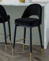 Stylish black velvet bar stools with gold-tipped legs, complementing a marble countertop in a modern setting.