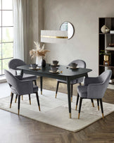 Stylish dark dining table with four upholstered gray chairs, gold accents, and elegant pendant light above. Cozy rug beneath.