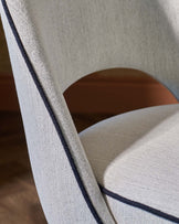 Stylish chair featuring light fabric with dark trim, emphasizing elegant curves and modern design.