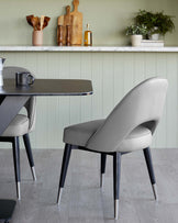 Modern dining set featuring a sleek, dark-grey tabletop with rounded corners and angled matte black legs with metallic tips, paired with an elegantly curved light grey upholstered chair with matching black legs tipped with silver.