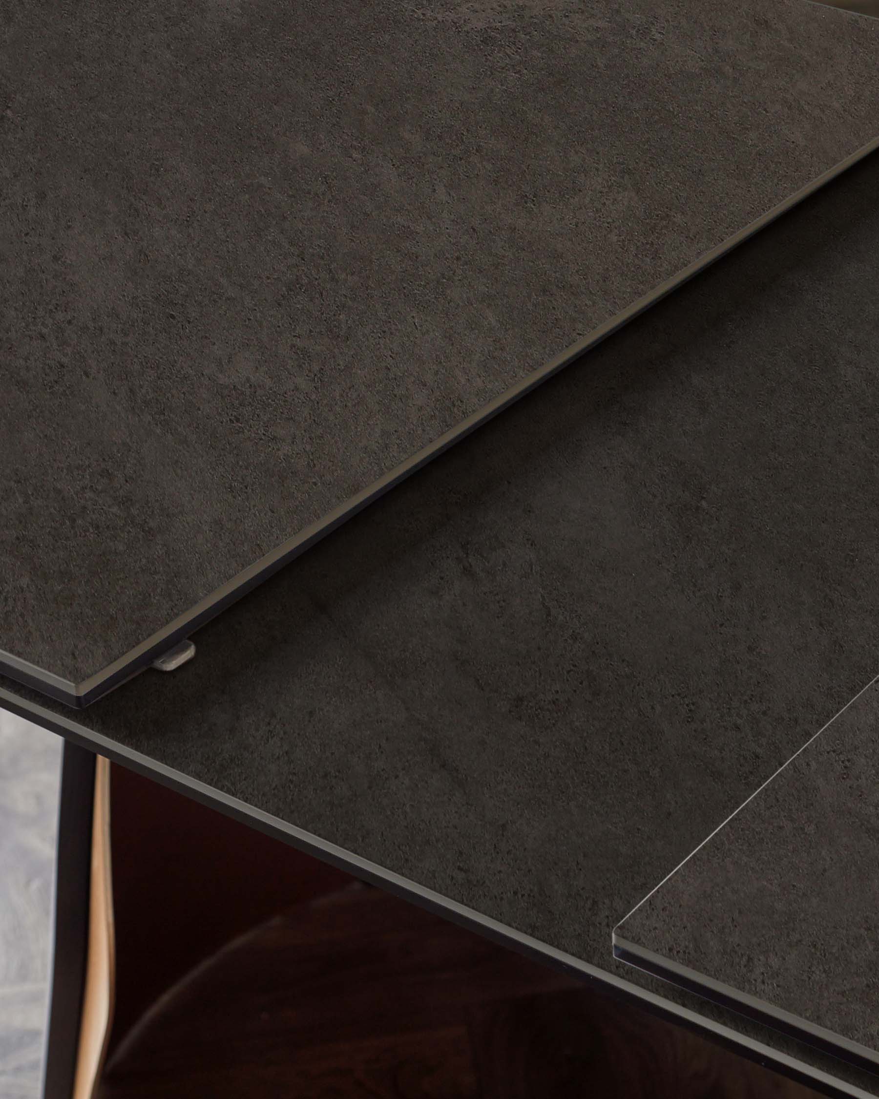 A contemporary dark stone tabletop with sleek edges, highlighting a modern aesthetic suitable for dining or workspaces.