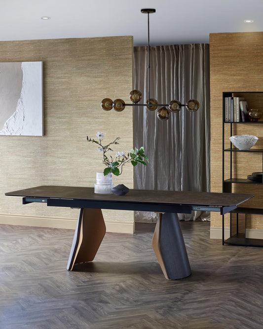 A modern dining table with unique, angular legs, complemented by decorative elements, a stylish chandelier, and textured wall.