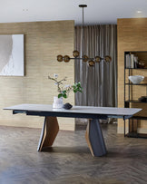 A contemporary dining table with a sleek white top and uniquely designed wooden legs, complemented by a stylish chandelier above.