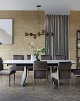 Sleek dining table with expandable feature, upholstered grey chairs, and a modern pendant light, set against a textured wall.