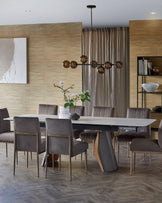 Sleek modern dining table with a unique base, paired with elegant gray upholstered chairs and a contemporary chandelier above.