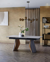 Modern dining table with a sleek white top and unique, geometric two-tone legs; complemented by a stylish pendant light overhead.