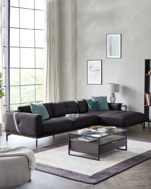 Modern living room featuring a sleek black sectional sofa, coffee table with glass top, decorative cushions, and plush area rug.