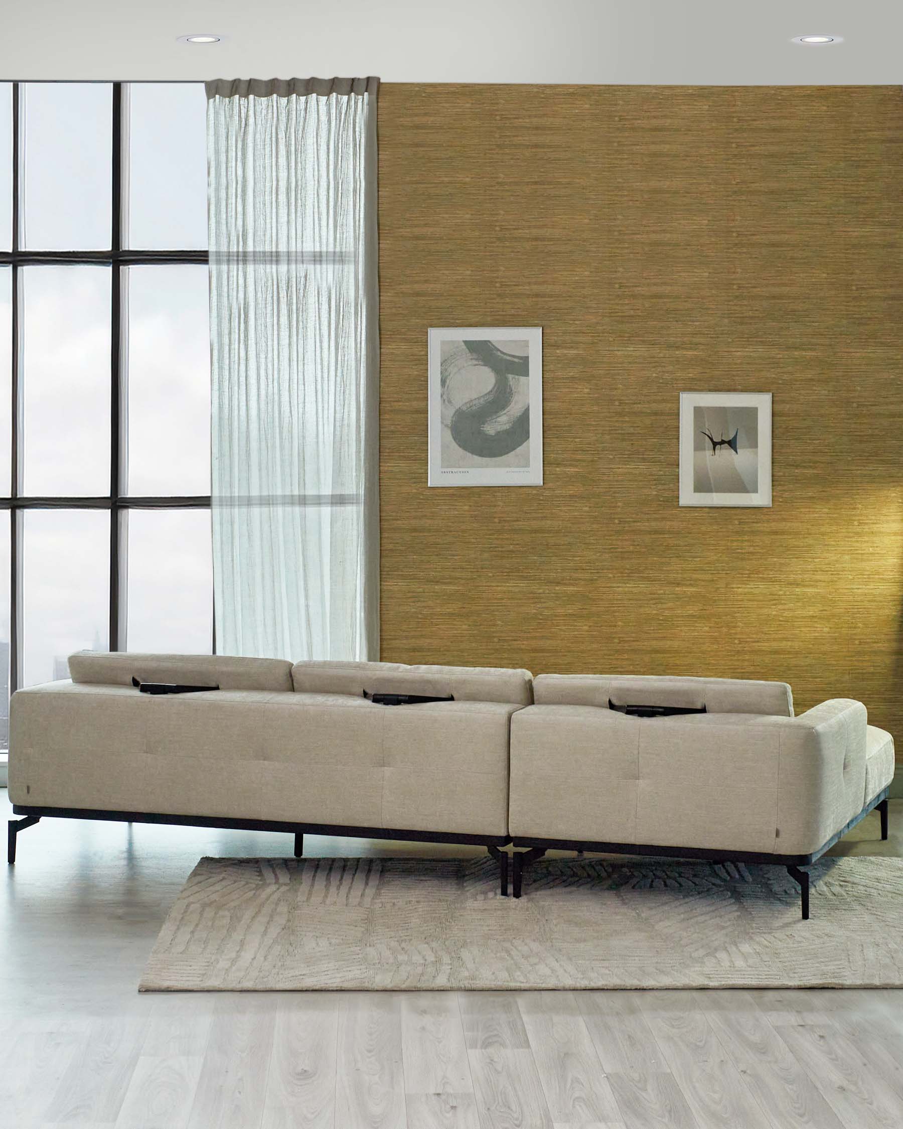 A modern sectional sofa with a light beige upholstery and a sleek black frame, featuring clean lines and elevated legs that create a sense of space. The sectional has multiple cushions providing a comfortable seating area, complemented by a large, textured area rug underneath in a faded cream colour, enhancing the minimalist aesthetic.