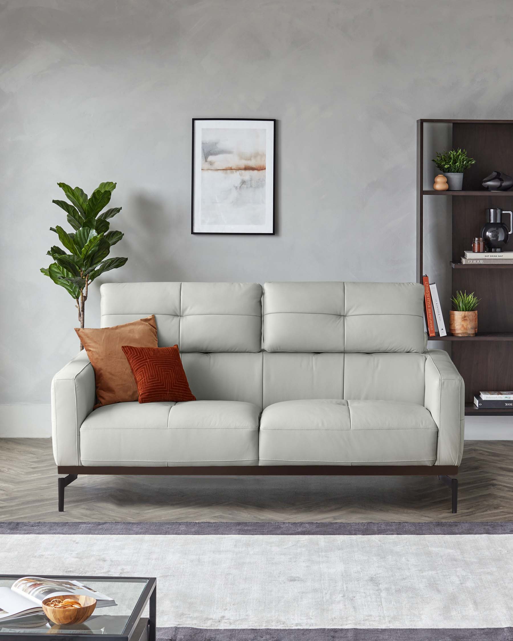 Modern light grey upholstered three-seater sofa with two textured throw pillows, elevated on dark wooden legs, paired with a dark wooden side shelving unit displaying decorative items, adjacent to a glossy-surface coffee table with a book and bowl, over a muted area rug.