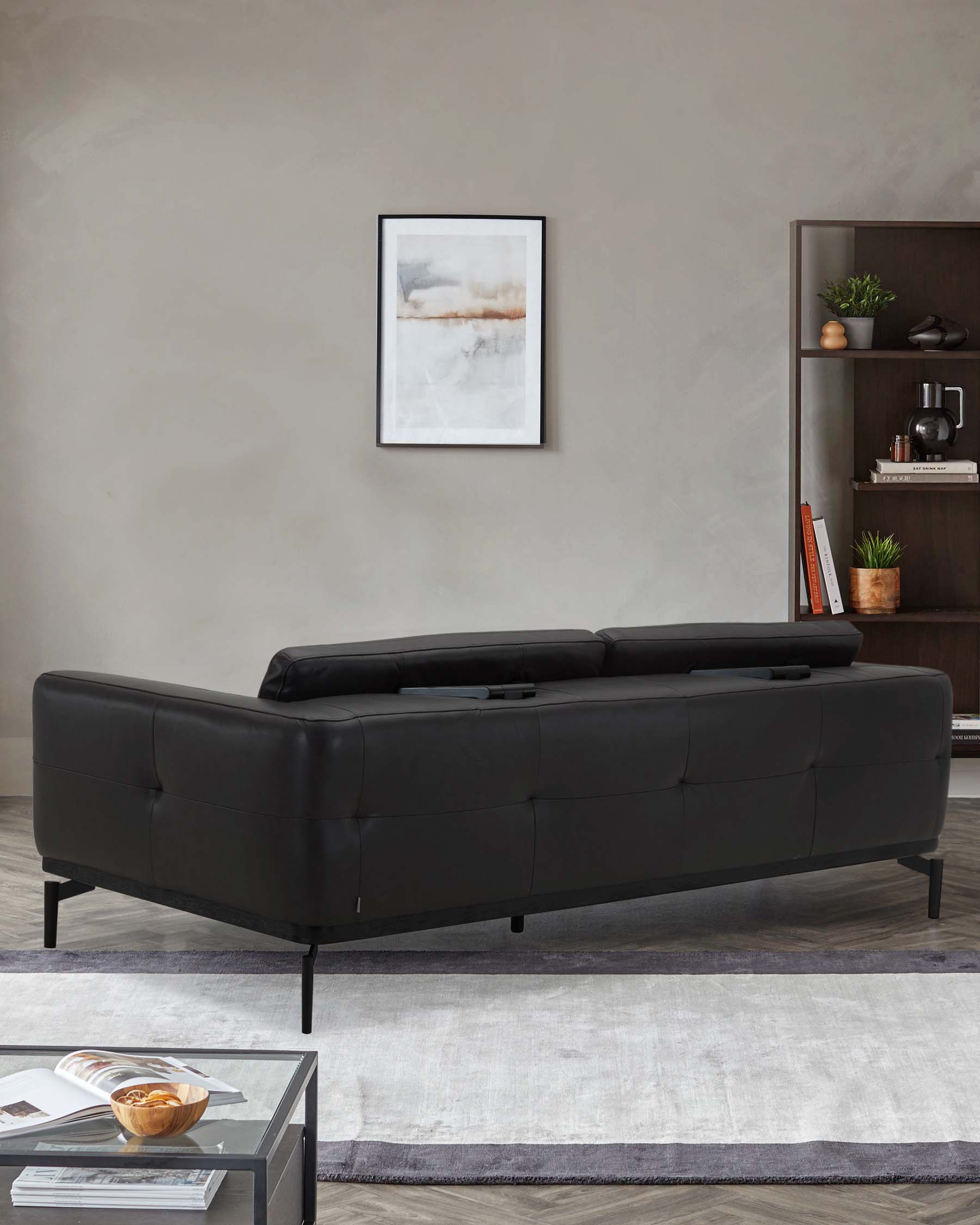 A sleek black leather sofa with tufted detailing, complemented by a stylish coffee table and a modern bookshelf.